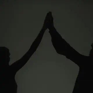 Two people doing a high-five, palms meeting with all fingers