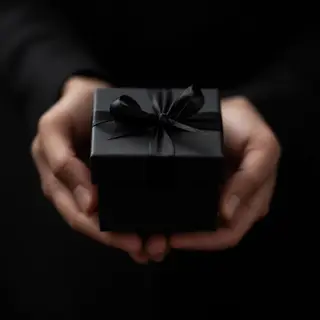 One person handing a small gift box to another person, both 
