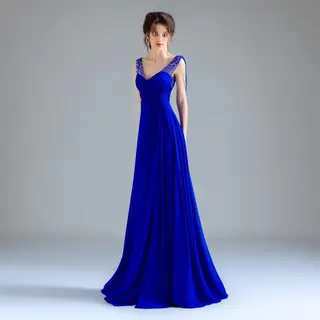 A woman wearing a royal blue evening dress against a neutral