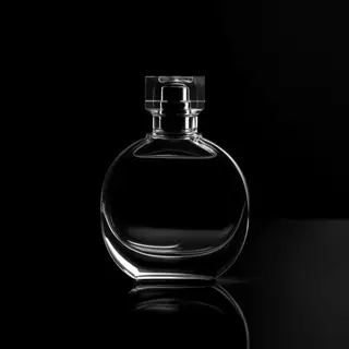 A clear glass perfume bottle on a reflective black surface w