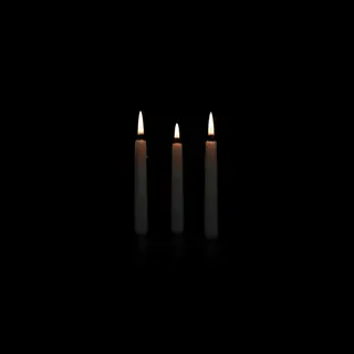 Exactly 4 white candles standing on a dark surface