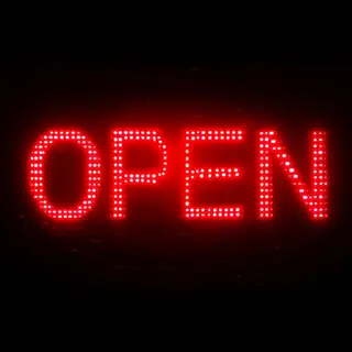 The word 'OPEN' displayed on a red LED sign with glowing pix