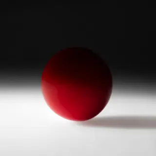A red sphere on a white surface with a single shadow cast to