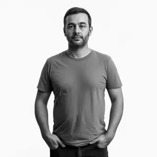 A man standing straight facing the camera, hands in pockets,