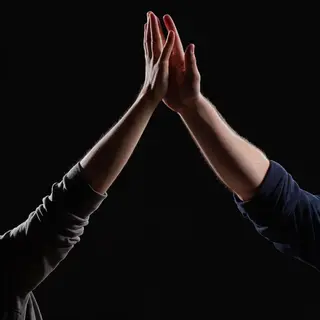 Two people doing a high-five, palms meeting with all fingers