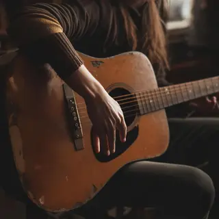 A person playing an acoustic guitar with left hand on the fr