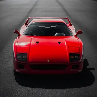 A bright red sports car parked on a gray asphalt road — the 