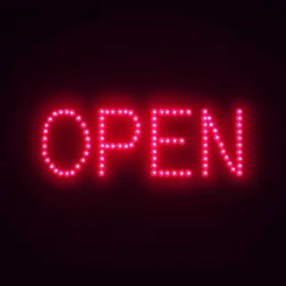 The word 'OPEN' displayed on a red LED sign with glowing pix