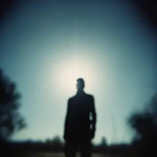 A person standing outdoors at midday with a short shadow dir