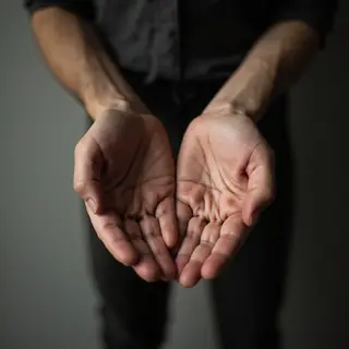 A person standing with both hands visible at their sides, fi