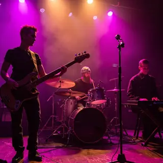 Three musicians on stage: a tall woman with short pink hair 