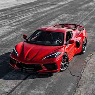 A bright red sports car parked on a gray asphalt road — the 