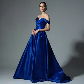 A woman wearing a royal blue evening dress against a neutral