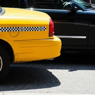 A yellow taxi and a black limousine parked next to each othe