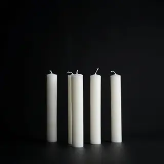 Exactly 4 white candles standing on a dark surface