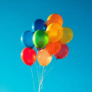 Exactly 11 colorful balloons floating against a clear blue s