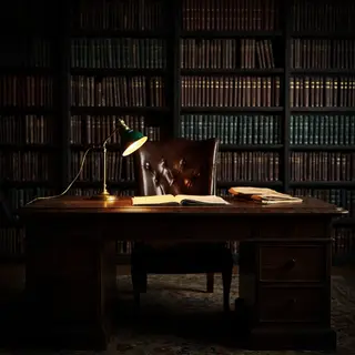 An office workspace with a desk, chair, bookshelf, and lamp 