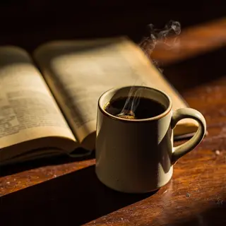 A coffee mug next to an open book on a desk