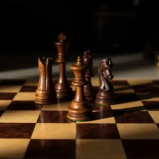 Five chess pieces on a board: a king in the center, a queen 