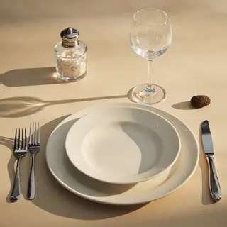 A dinner table scene with a plate, fork, knife, wine glass, 