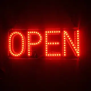 The word 'OPEN' displayed on a red LED sign with glowing pix