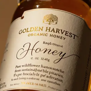 A product label for 'GOLDEN HARVEST ORGANIC HONEY' with subt
