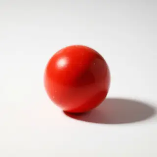 A red sphere on a white surface with a single shadow cast to