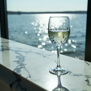 A crystal wine glass on a polished marble counter next to a 