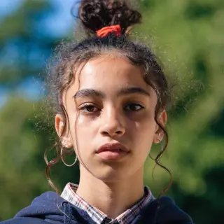 A headshot of a teenager with a relaxed, neutral face