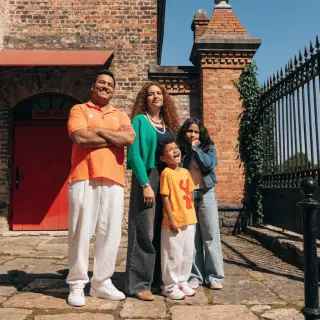 A family photo with four people: a father beaming with pride