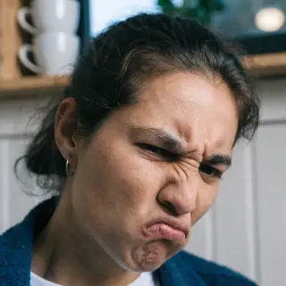 A close-up of a person's face showing clear disgust, nose wr
