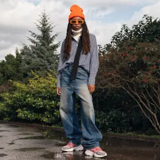 A person standing in a neutral pose in a park, full body vis