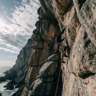 A rock climber clinging to a cliff face with arms and legs e
