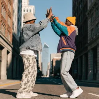 Two people doing a high-five, palms meeting with all fingers