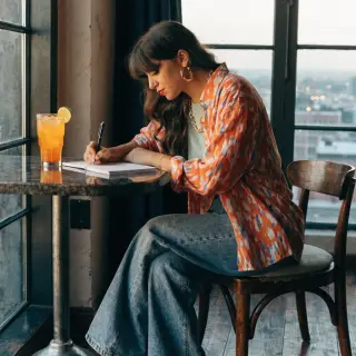 A woman writing in a notebook with a pen gripped correctly i