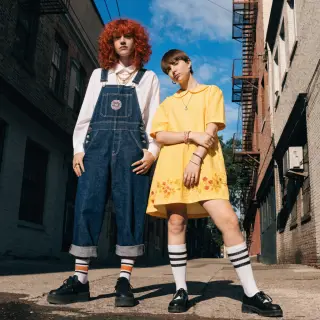Two friends posing: one tall with curly red hair in denim ov