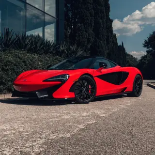 A bright red sports car parked on a gray asphalt road — the 