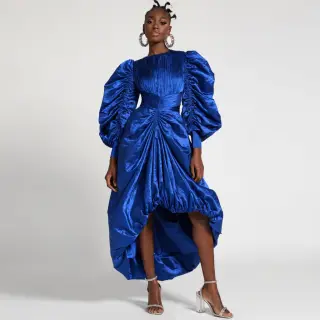 A woman wearing a royal blue evening dress against a neutral
