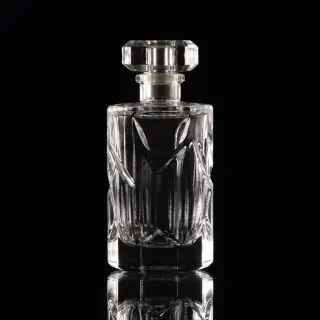 A clear glass perfume bottle on a reflective black surface w
