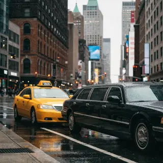 A yellow taxi and a black limousine parked next to each othe