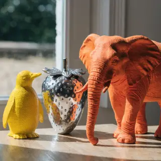An orange elephant, a yellow penguin, and a silver strawberr