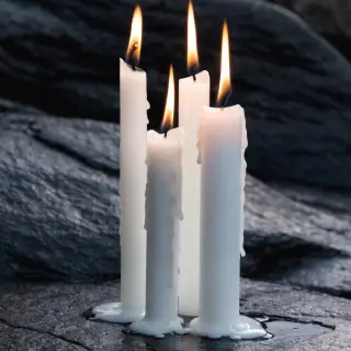 Exactly 4 white candles standing on a dark surface