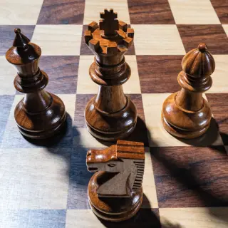 Five chess pieces on a board: a king in the center, a queen 