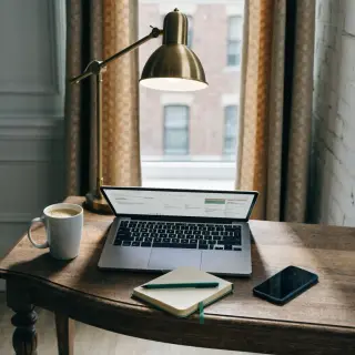 A desk scene: laptop in the center, coffee mug to the left, 