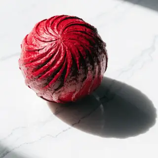 A red sphere on a white surface with a single shadow cast to