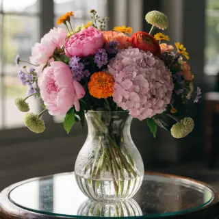 A vase of flowers on a glass table with a clear reflection v