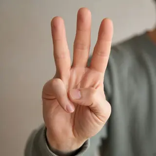 A person counting to three on their fingers, with index, mid